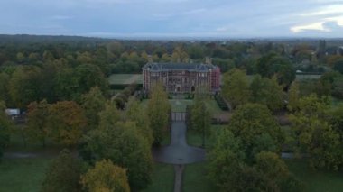Aerial of Ham House Ulusal Vakfı. İnsansız hava aracı sonbahar ağaçlarının arasından şafağın gri ışığında yükselerek tarihi evleri ve bahçeleri gözler önüne seriyor.