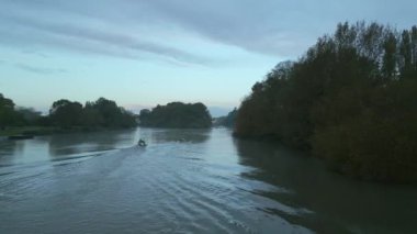 Şafağın gri ışığında Thames Nehri 'nde kürek çeken tekne. Koçun teknesi arkasında seyahat ediyor. Sonbahar Ağaçları.