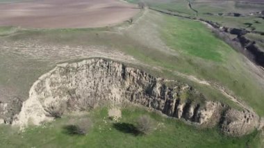 Bu büyüleyici dron çekimi, arka planda görkemli yuvarlanan tepeleri olan canlı yeşil bir çayırın geniş manzarasını yakalar..