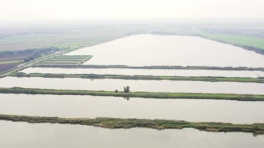 Sis içindeki taşra yollarıyla ayrılmış balık göletlerinin hava görüntüleri