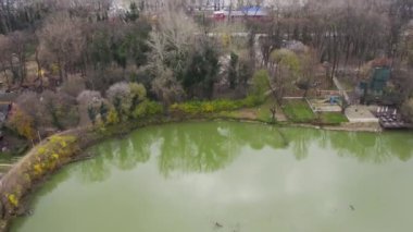 İnsansız hava aracı, huzurlu bir banliyö gölünden başlayıp büyük bir şehri ortaya çıkarmak için yükseliyor.