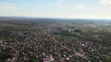 Sonbaharda bir köyün büyüleyici hava manzarası, bulutlu parlak mavi gökyüzü ve arka planda bir