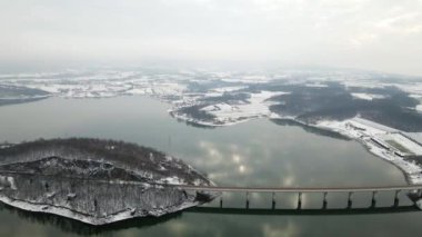 Kış manzarasında bir göl üzerindeki bir köprünün havadan görünüşü