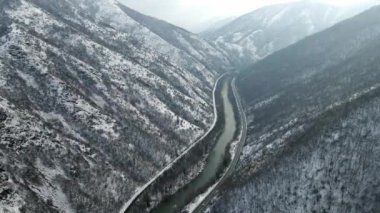 Dağın eteklerinde akan bir nehrin havadan görünüşü. Her iki tarafında yollar var.