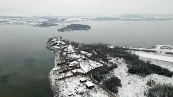 Kışın Göl Kıyısında Karla Kaplı Küçük Evlerin Havadan Görünüşü — Stok video