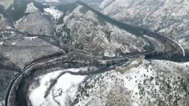 Karla kaplı dağların tepesinde ortaçağdan kalma bir şatonun bulunduğu havadan bir kış manzarası.
