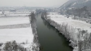 Bir dron kış manzarasında nehir yüzeyine doğru uçuyor.