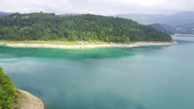 Sırbistan 'ın Zaovine kentinde ağaçlarla çevrili mavi göl kıyısının insansız hava aracı görüntüleri