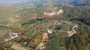 Tepedeki ağaçlarla çevrili küçük evler ve tarım arazilerinin insansız hava aracı görüntüleri.