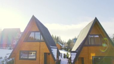 Sırbistan 'ın Zlatibor dağındaki karla kaplı turistik köyde güneşli bungalovlar
