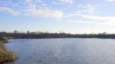 Sırbistan 'ın Zrenjanin kentinde mavi bulutlu gökyüzünün altında dalgalı bir göl yüzeyi