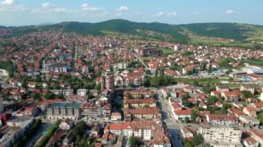Drone kasabadaki evleri ve binaları yakalıyor. Arka planda Arandjelovac ve dağları.