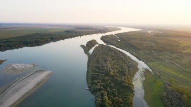 İnsansız hava aracı Tuna nehrinin üzerinden uçar ve gün batımında etrafını çayırlarla ve ormanlarla sarar.