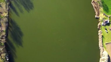 Bir gölün sakin, parlak yüzeyinde İHA uçuşu