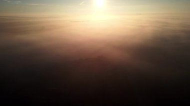 İnsansız hava aracı yükseklerde uçar ve yoğun sisi ve güzel günbatımını yakalar.