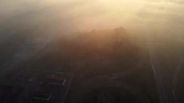 Yoğun siste gün batımında sıkışan trafiğin olduğu ağaçlık bir bölge.