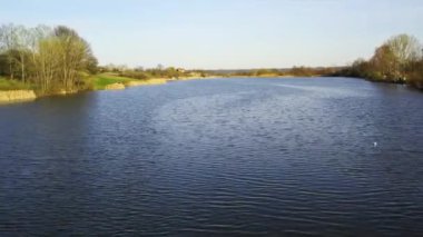 İHA dalgalanan mavi göl yüzeyinin üzerinde uçar ve etrafını sarar.