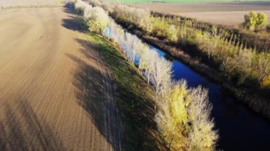 İnsansız hava aracı boş tarla ve ağaçlarla çevrili bir nehri yakalıyor.