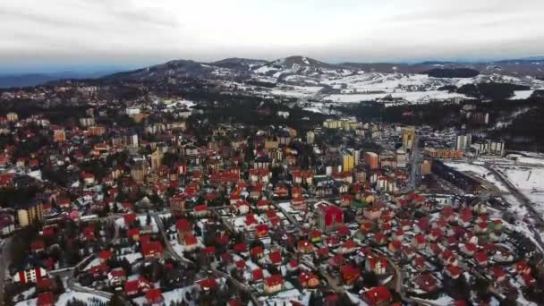 雪に覆われた山の町の建物の赤い屋根の空中ビュー — ストック動画