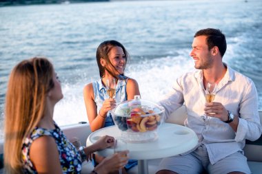 Bir genç adam ve iki güzel kadın şampanya içip teknede eğleniyorlar.