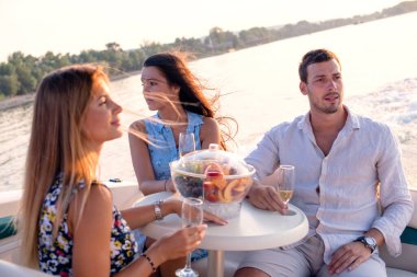 Bir genç adam ve iki güzel kadın şampanya içip teknede eğleniyorlar.
