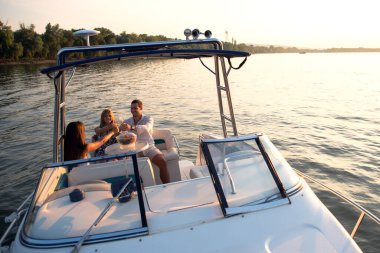 Genç bir adam ve iki güzel kadın teknede eğleniyor, yaz günbatımında parti veriyorlar.