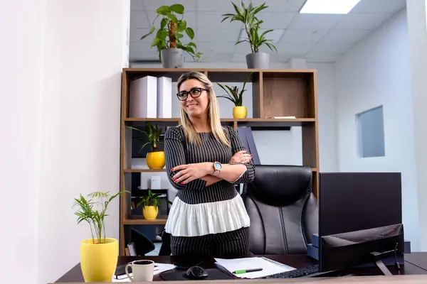 Çekici sarışın iş kadını ofisinde duruyor.