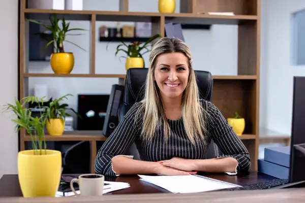 Mutlu kadın yönetici iş yerinde oturuyor.