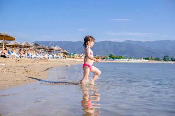 Küçük kız denize giriyor.