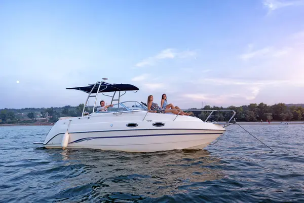 Genç bir adam ve iki kadın yaz günbatımında teknede eğleniyorlar.