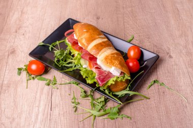 Ahşap masada lezzetli sandviçli güzel dekore edilmiş bir tabak.