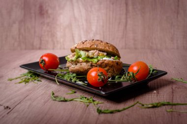 Domateslerle süslenmiş siyah tabakta nefis bir sandviç.