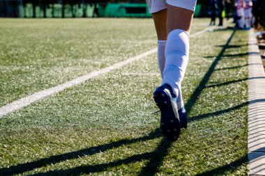 Beyaz çizginin yanında koşan bir futbolcunun bacakları