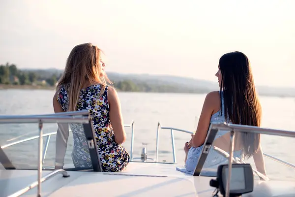 İki neşeli genç bayan arkadaş bir teknede oturup konuşuyorlar.