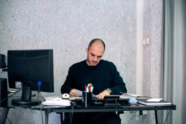 Ofisinde masa başında çalışan Kafkasyalı genç bir işadamı, elinde evrak tutuyordu..