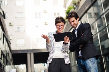 İş adamları açık havada tablet izliyor.