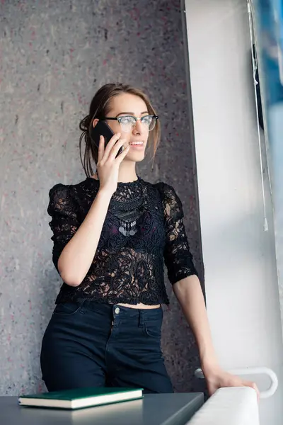 Kız telefonda konuşuyor. Pencere kenarında, ayakta.