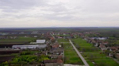 Gri bulutların altındaki yeşil tarlalarla çevrili köyün insansız hava aracı görüntüleri.