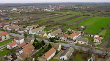 Traktörün, köyden geçen yolcularla dolu bir arabayı çekerken çekilmiş hava görüntüleri.