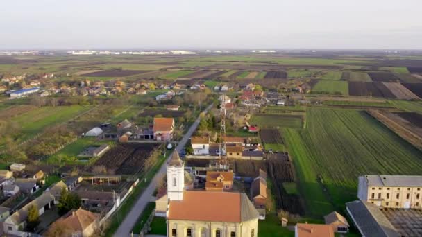 ドローンは平野の田舎に囲まれた村の教会の上を飛ぶ — ストック動画