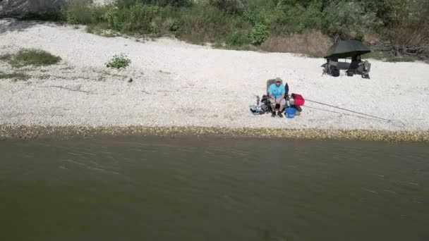 Bir Adam Gölün Kıyısında Oturuyor Balık Tutuyor Diğeri Şemsiyenin Altında — Stok video