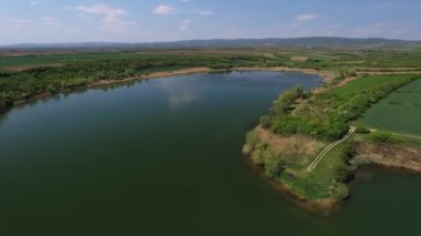 Açık mavi gökyüzünün altında temiz gölü gösteren güzel bir hava videosu.