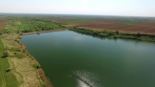 ドローンは栽培された畑と緑に囲まれたメディス湖を捕獲します — ストック動画