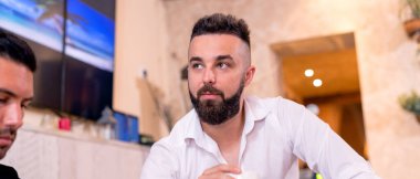 Kafede kahve içen genç adam..