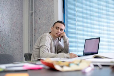 Ofiste rastalı saçı olan genç bir tasarımcı projesinde çalışıyor.