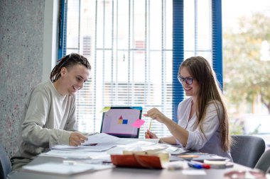 Ofisteki projede çalışan genç tasarımcılar gülümsüyor ve tartışıyorlar.