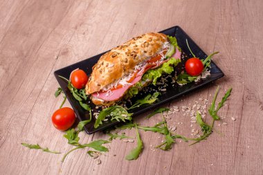 Ahşap masada lezzetli sandviçli güzel dekore edilmiş bir tabak.