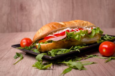 Ahşap masada lezzetli sandviçli güzel dekore edilmiş bir tabak.