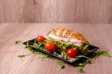 Ahşap masada lezzetli sandviçli güzel dekore edilmiş bir tabak.