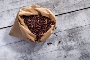 Coffee beans in sack on wooden clipart